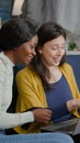 Two multiethnic women sitting on couch watching comedy series on laptop Royalty Free Stock Photo