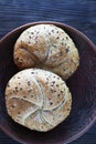 Two multigrain buns with sesame seeds and flaxseed on a brown plate Royalty Free Stock Photo
