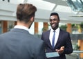 Two multinational young businessmen discussing business at meeting in office.