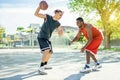 Two multiracial cheerful friends playing basketball outdoor in city urban contest with back light - Young people having fun doing