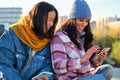 Two multiracial female friends laughing and sharing something on the smartphone. Royalty Free Stock Photo