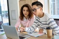 Two multiracial students using computer sitting together at desk in classroom.