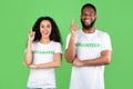Two Multiracial Volunteers Having Idea Pointing Fingers Up, Green Background
