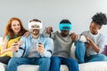 Two guys playing video games using VR glasses and girlfriends support them. Royalty Free Stock Photo