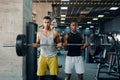 Two muscular men poses with heavy barbell in gym Royalty Free Stock Photo