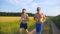 Two muscular men running and talking outdoors. Young athletic guys jogging over the field. Male sportsmans training