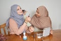 Two muslim female friends applying make up to each other.