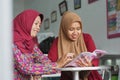 Two Muslim Hijab woman reading a magazine sitting inside their fashion store Royalty Free Stock Photo