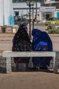 Two muslim women talking on a bench