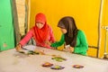 Two Muslim young girls painting Batik fabric