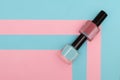 Two nail polish bottles on striped pink and blue background. Pink and blue nail polish bottle on striped background. Copy space Royalty Free Stock Photo