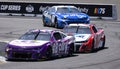 two nascar cars racing down a track next to landowners Royalty Free Stock Photo