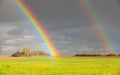 Two natural rainbow over green field after rain