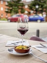 Two near glasses of red wine, bottle of wine and chef`s compliment, small plate of paella served on table outdoor Royalty Free Stock Photo