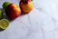 Two nectarines on white marble surface