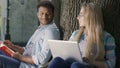 Two nerds flirting with each other sitting on campus park and doing homework