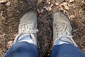 Two neutral gray dirty barefoot shoes on brown forest floor . Hiker foot foto photographed from bird perspective . Letting go and