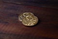 Two new golden physical bitcoins lies on dark wooden backgound, close up. High resolution photo. Cryptocurrency mining concep