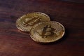 Two new golden physical bitcoins lies on dark wooden backgound, close up. High resolution photo. Cryptocurrency mining concep