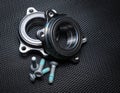 Two new hub bearings with spare mounting bolts, for a sports car. Black background, metal mesh Royalty Free Stock Photo