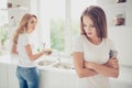 Two nice lovely attractive charming sad people blonde mom mum wiping plates kitchenware teenage girl avoiding work in Royalty Free Stock Photo