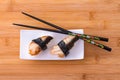 Two nigiri eel sushi with chopstick on bamboo board