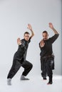 Two ninjas stand with a foot in front and a fighting post on a gray background Royalty Free Stock Photo