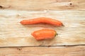 Two non-standard ugly carrots are lying horizontally on tree bark.