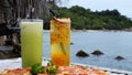 Two nonalcoholic cocktails glasses with straws and fresh pizza on beach cafe table. Tropical resort vacation calm sea Royalty Free Stock Photo