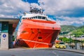 Two Norwegian paramedics in red uniforms are resting near an ambulance parked in a port near a large ship. Theme healthcare and