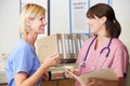 Two Nurses Discussing Patient Notes At Nurses Station Royalty Free Stock Photo