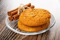 Oat cookies with sunflower seeds, cinnamon sticks in transparent saucer on wooden table