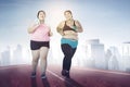 Two obese women jogging together outdoors