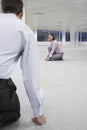 Two office workers measuring floor in empty office space back view