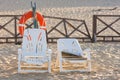 Two old beach chairs stand near lifeline on the sandy beach Royalty Free Stock Photo