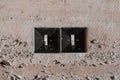 Two old black plastic square minimalist switches on a tuff-lined wall in a modernist Soviet-era interior, close up, textured