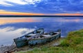 Two old blue-green boats moored by a metal chain to the shore of a calm river against the backdrop of the bright rising sun Royalty Free Stock Photo