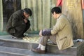 Two old chinese men playing on the floor in the Green Lake Park the sign on the tree means `citizens`