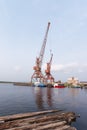 Two old cranes for loading timber onto barges stand on a river pier against the backdrop of mountains. Summer, Siberia, Buryatia,