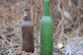 two old dirty glass bottles stand on the gray ground Royalty Free Stock Photo