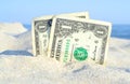 Two old dollar bills in sand on background of sea blue sky on sunny summer Royalty Free Stock Photo