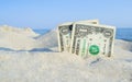 Two old dollar bills in sand on background of sea blue sky on sunny summer Royalty Free Stock Photo