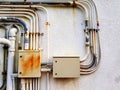 Two old electrical boxes installed and distributed the power cable via old stainless steel pipe lines on white concrete with copy Royalty Free Stock Photo