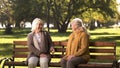 Two old fiends talking and laughing sitting on bench in park, retirement age