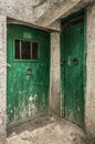 Two old green timber doors in the scuffed wall