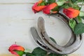 Two old horse shoes paired with silk red roses on a white-washed rustic wooden background