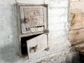 Old iron doors of the firebox and ash-pan in a Russian stove, whitewashed with lime, in a country house