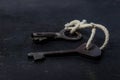 Two old keys tied with a white rope. The keys are on a black background Royalty Free Stock Photo