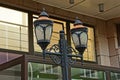 Two old lanterns made of black iron and white glass on a pillar in the street against the wall of the building Royalty Free Stock Photo