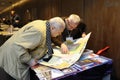 Two old men looking at the map placed on a counter during bookfair